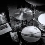 Drum kit set up on stage with Ableton Live on macbook pro black and white greyscale